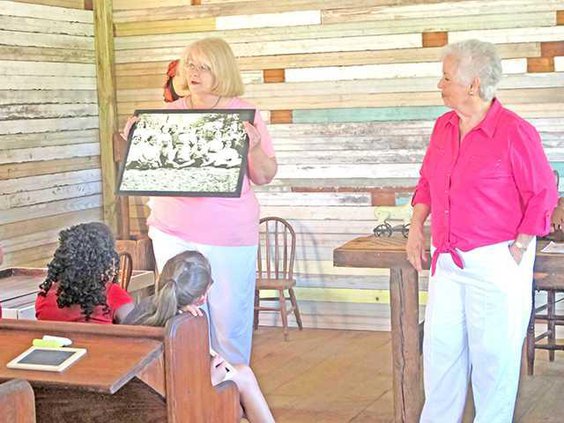 Julie Martin left and Barbara Martin right show a picture of students who attended the one-room school house