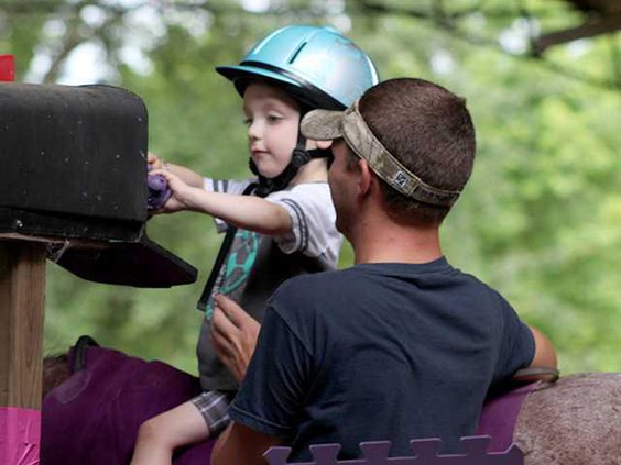 A young rider checking the mail box while horseback