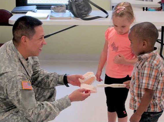 CDC kids show Sgt. Galarza how to properly brush teeth