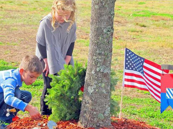 Capt. james Adamouskis wreath -- kids of LTC Geoff Van Epps kids placing damdelion flowers by tree