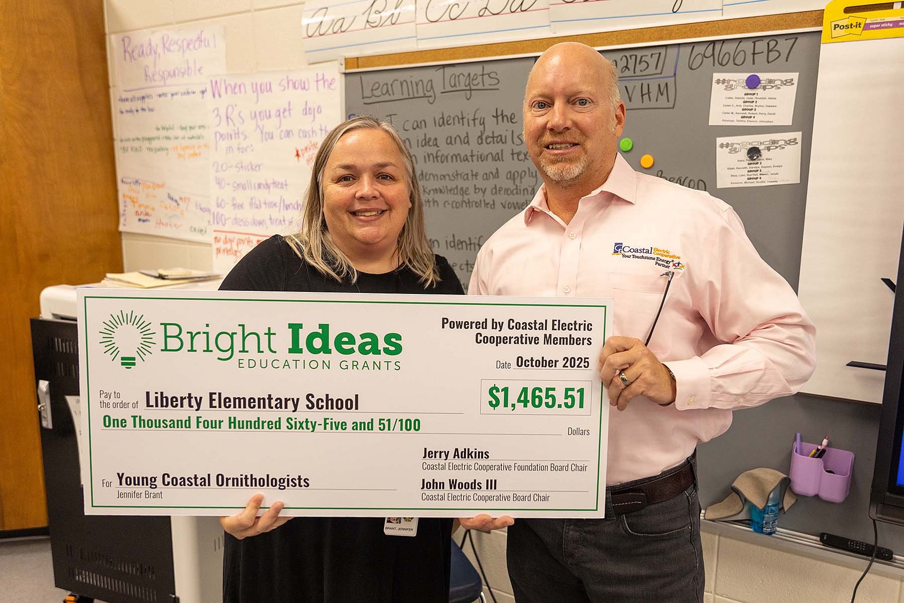 Coastal EMC CEO Chris Fettes present a Bright Ideas grant check for $1,465.51 to Liberty Elementary’s Jennifer Brant.