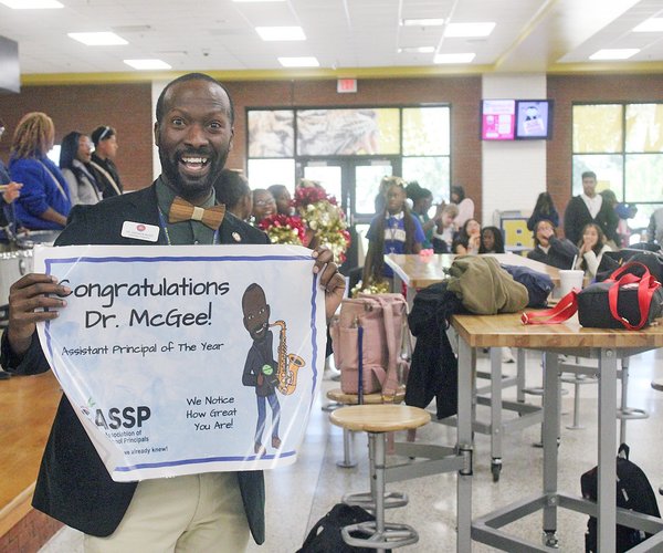 Dr. DeShaun McGee, an assistant principal at Bradwell Institute, holds up the banner for his statewide achievement.  Photo by Pat Donahue